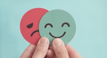 the hand keeping a sad and happy paper face