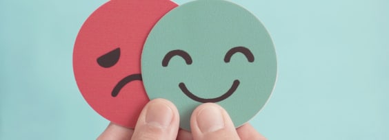 the hand keeping a sad and happy paper face