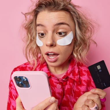 the girl looking on a phone and holding a credit card