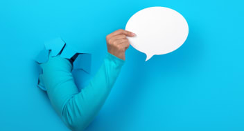 a hand holding a paper chat bubble
