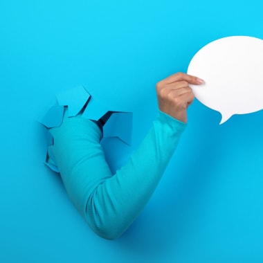a hand holding a paper chat bubble