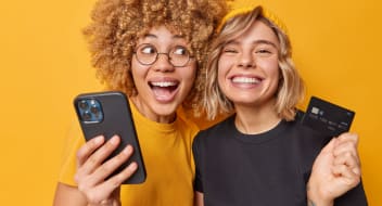 two young girls holding a telephone and a credit card